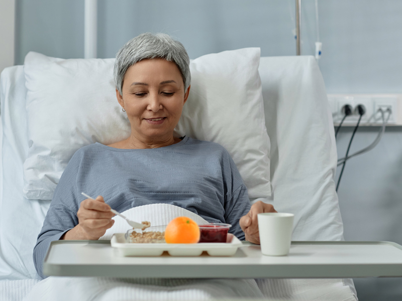 Woman in bed at hospice eating a Mom’s Meals site-delivered meal